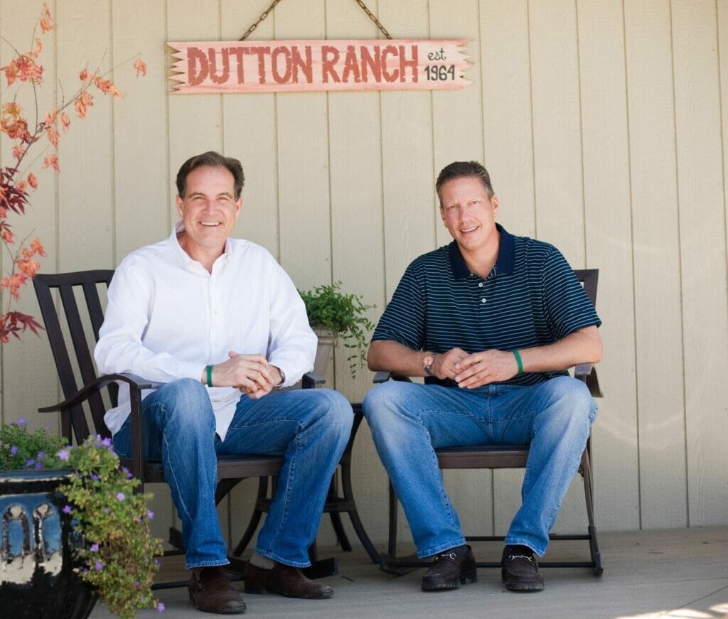 Jim Nantz & Peter Deutsch sitting in chairs and smiling at camera